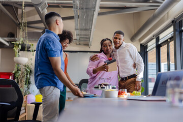 Obraz premium Celebrating at office, diverse colleagues sharing joyful moment with cake and gifts