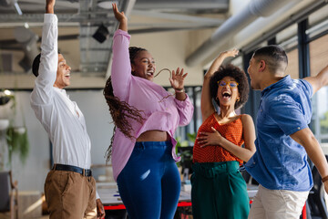 Celebrating success, diverse colleagues expressing joy and excitement in modern office