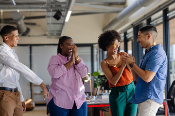 In office, diverse colleagues celebrating success, sharing joyful moments together