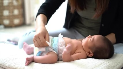 A caregiver gently changes a diaper for a newborn baby, ensuring comfort and cleanliness. The setting is peaceful and intimate, focusing on the tender moment