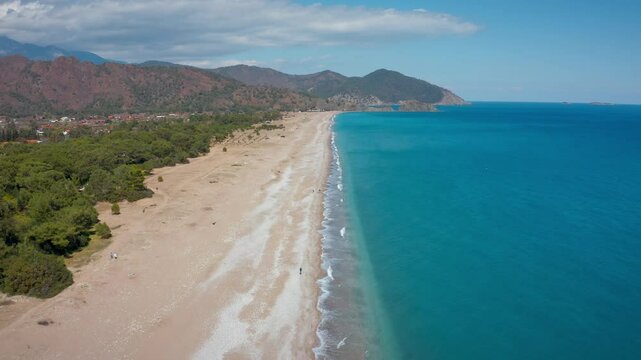 The wide coastline of Olympos was captured from a bird's eye view by a drone. This magnificent view of turquoise sea, long sandy beach, lush trees and mountains