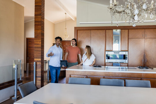 Real estate agent showing modern kitchen to couple, discussing home features