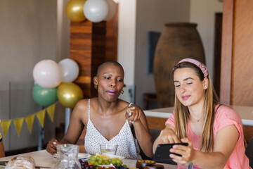 Two friends enjoying lunch together, sharing moments and looking at smartphone