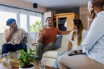 Naklejka premium Friends having animated discussion on couch at home, sharing ideas and opinions