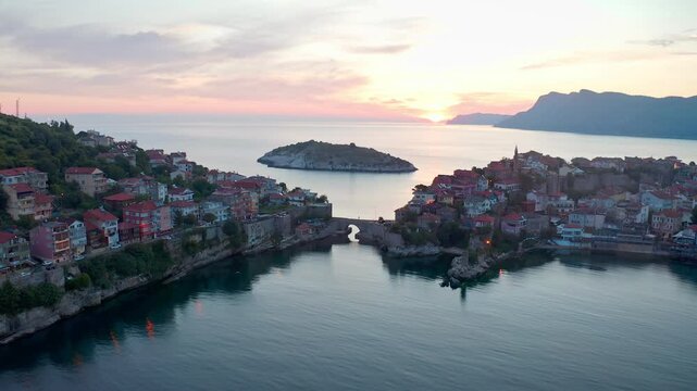 A drone approaching a historical bridge in Amasra. The colors reflected in the calm waters of the Black Sea, the timeless silhouette of Amasra's historical stone bridge and picturesque houses