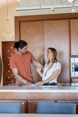 Preparing meal, couple laughing together in modern kitchen, sharing joyful moment