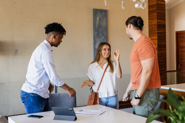 Friends greeting each other with smiles and handshakes in modern living room