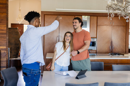Real estate agent showing happy couple new home in modern kitchen