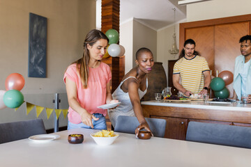 Friends preparing snacks and setting table for indoor gathering at home
