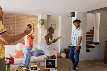 Friends celebrating new job with cake and balloons in cozy living room