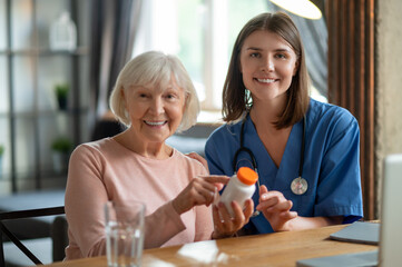 Female doctor visiting elderly patient at home giving medication