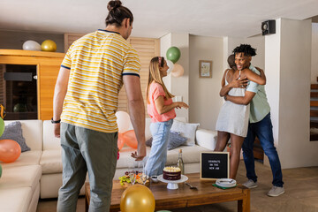 Friends celebrating new job with cake and balloons, sharing hugs and smiles