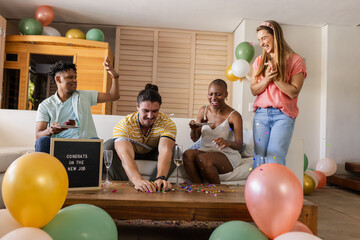 Fototapeta premium Celebrating new job, diverse friends enjoying party with cake and confetti at home