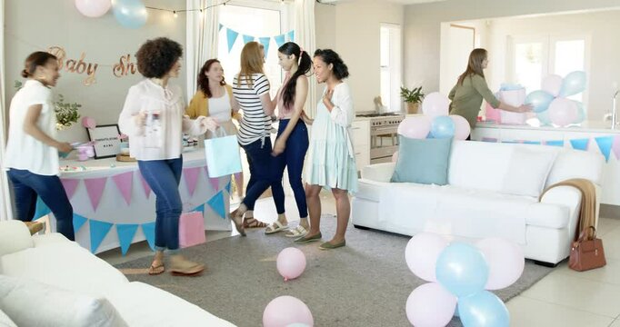 Group of happy multiracial and white female friends with baby giving presents and embracing at a bab