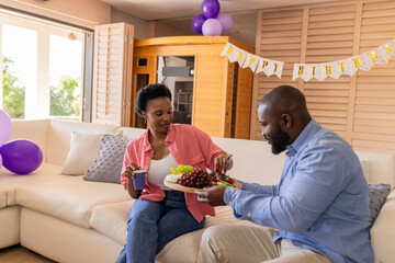 Celebrating birthday, couple enjoying fruit platter and drinks at home party