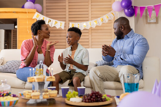 Celebrating birthday, happy family clapping and smiling with cake and decorations