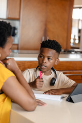 In school, African American boy discussing homework with mother at kitchen table