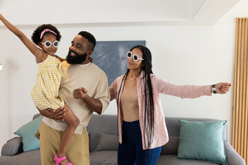 Happy African American family dancing together at home, wearing stylish sunglasses © wavebreak3