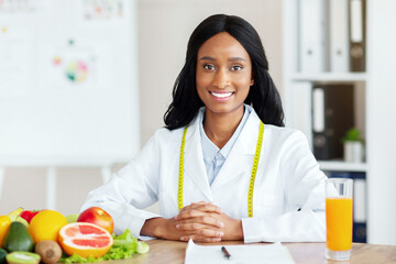 Portrait of young black weight loss consultant smiling at camera in modern clinic, space for text....
