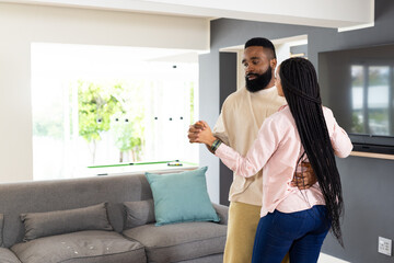 African American couple dancing together at home, enjoying joyful moment © WavebreakMediaMicro