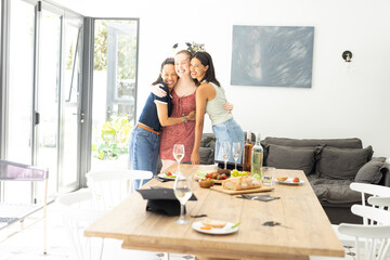 Hugging each other warmly, three young women celebrate indoors with joyful smiles