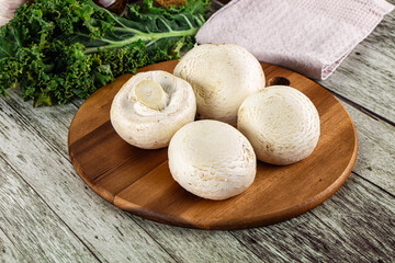 White champignon mushrooms heap over board