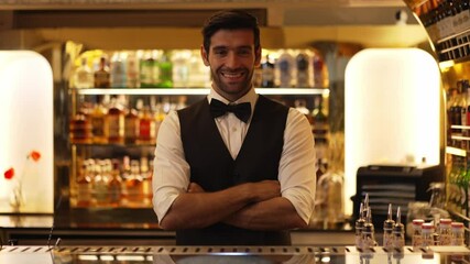 Profile good looking smiling smart bartender wiping glass at luxurious beverage counter bar scene looking at camera to pose neat professional barman costume greeting warm at bar nightclub. Vinosity.