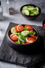 Tomato onion cucumber salad in a bowl on a grey background