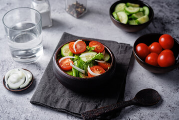 Tomato onion cucumber salad in a bowl on a grey background