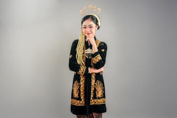 Elegant young Asian woman in traditional Javanese attire smiling calmly. Her confident expression and graceful pose reflect cultural pride, perfect for heritage or fashion ads.