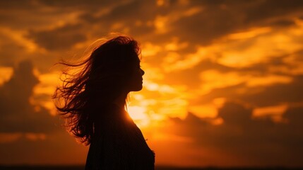 Fototapeta premium Silhouette of a woman at sunset, bathed in golden light.