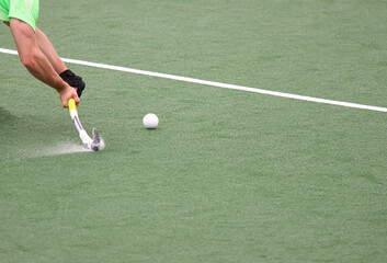 Field hockey player hitting the ball with the stick