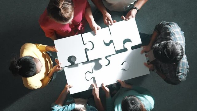 Top view of business people separated jigsaw together at meeting. Aerial view of diverse team put piece of jigsaw puzzle together out and standing while wearing casual cloth at conference. Symposium.
