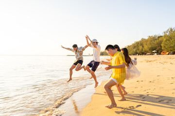 Happy Asian man and woman playing water in the sea on summer beach holiday vacation at sunset. Group of People friends enjoy and fun outdoor active lifestyle travel nature ocean tropical island beach.
