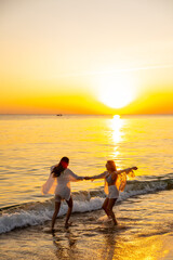 Happy Asian woman travel nature the sea on summer beach holiday vacation. Lesbian couple enjoy and fun outdoor lifestyle dancing and playing water in the sea at tropical island beach at summer sunset.