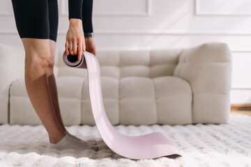 Woman preparing for home fitness exercise on yoga mat in a cozy living room