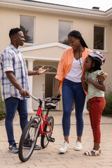 Fototapeta premium African American family enjoying time together with bicycle outside their home