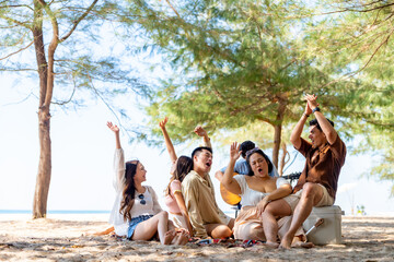 Happy Asian man and woman travel at the sea on summer beach holiday vacation. Group of People friends enjoy and fun outdoor lifestyle relaxing and picnic together on tropical island beach in sunny day