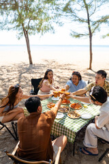 Happy man and woman travel at the sea on summer beach holiday vacation. Group of Asian people friends enjoy and fun outdoor lifestyle having lunch eating seafood together on tropical island beach. © CandyRetriever 