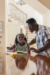 Father helping daughter with homework at home, discussing and learning together