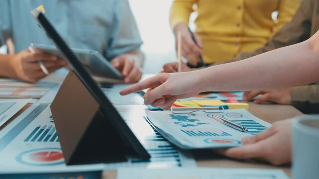 A dynamic scene of a collaborative meeting showcasing diverse hands engaged in discussion over data charts and digital devices in a modern office setting. SACTR