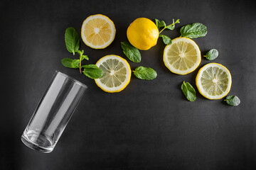 Fresh juicy lemon and mint leaves on black background. Ingredients for summer cocktail. Food...