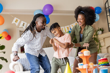 African American family celebrating birthday at home, smiling and dancing together