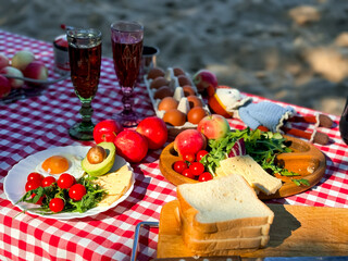 Outdoor picnic with fresh avocado, tomatoes, eggs, and bread on checkered cloth