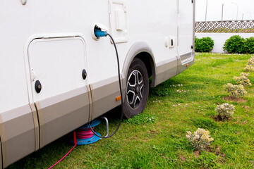 Camper van power connection on grass with electric cable reel for outdoor use