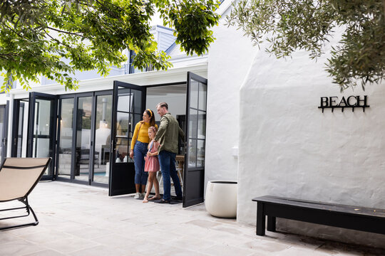 Family enjoying sunny day outside modern beach house, preparing for fun outing