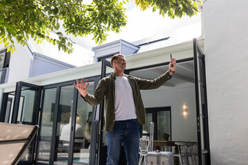 Fototapeta premium Man outdoors taking selfie with smartphone, smiling and enjoying sunny day