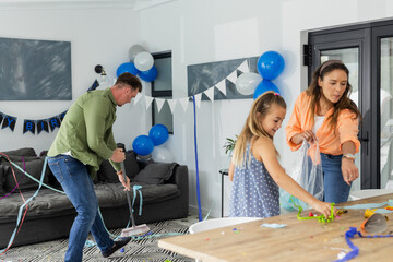 Family cleaning up after birthday party at home, surrounded by decorations