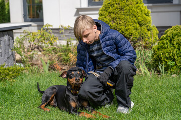 Bonding Moments: Teenager Tending to a Miniature Pinscher in a Tranquil Garden Setting