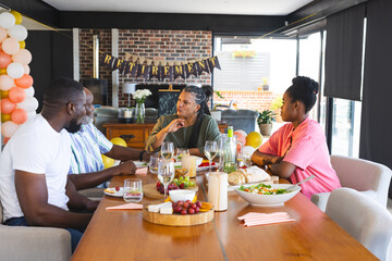 Family enjoying retirement celebration with food and conversation at dining table